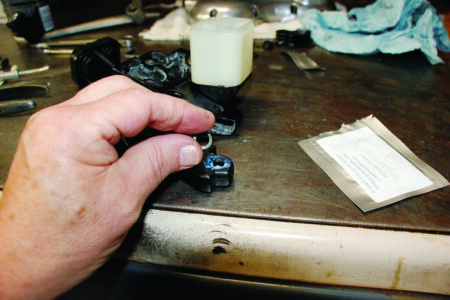 hand and two fingers holding round gray washer above handle bar